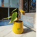 A vibrant Philodendron Red Emerald plant sapling with green and reddish leaves, potted in a bright yellow pot featuring the green "Pick Your Plant" logo, placed on a white marble surface near a window with a brick wall in the background.